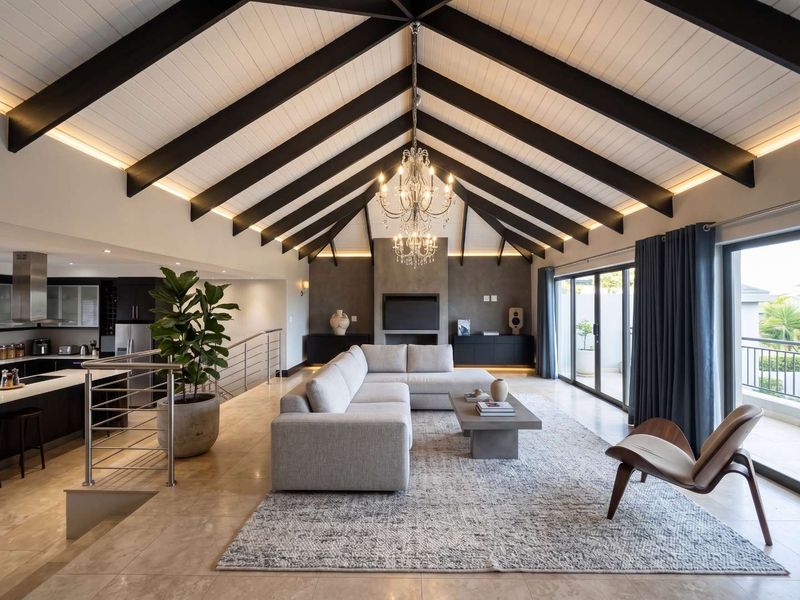 Spacious open-plan living area featuring a dramatic vaulted ceiling with exposed beams, stone flooring, a built-in fireplace, and seamless flow to the kitchen.