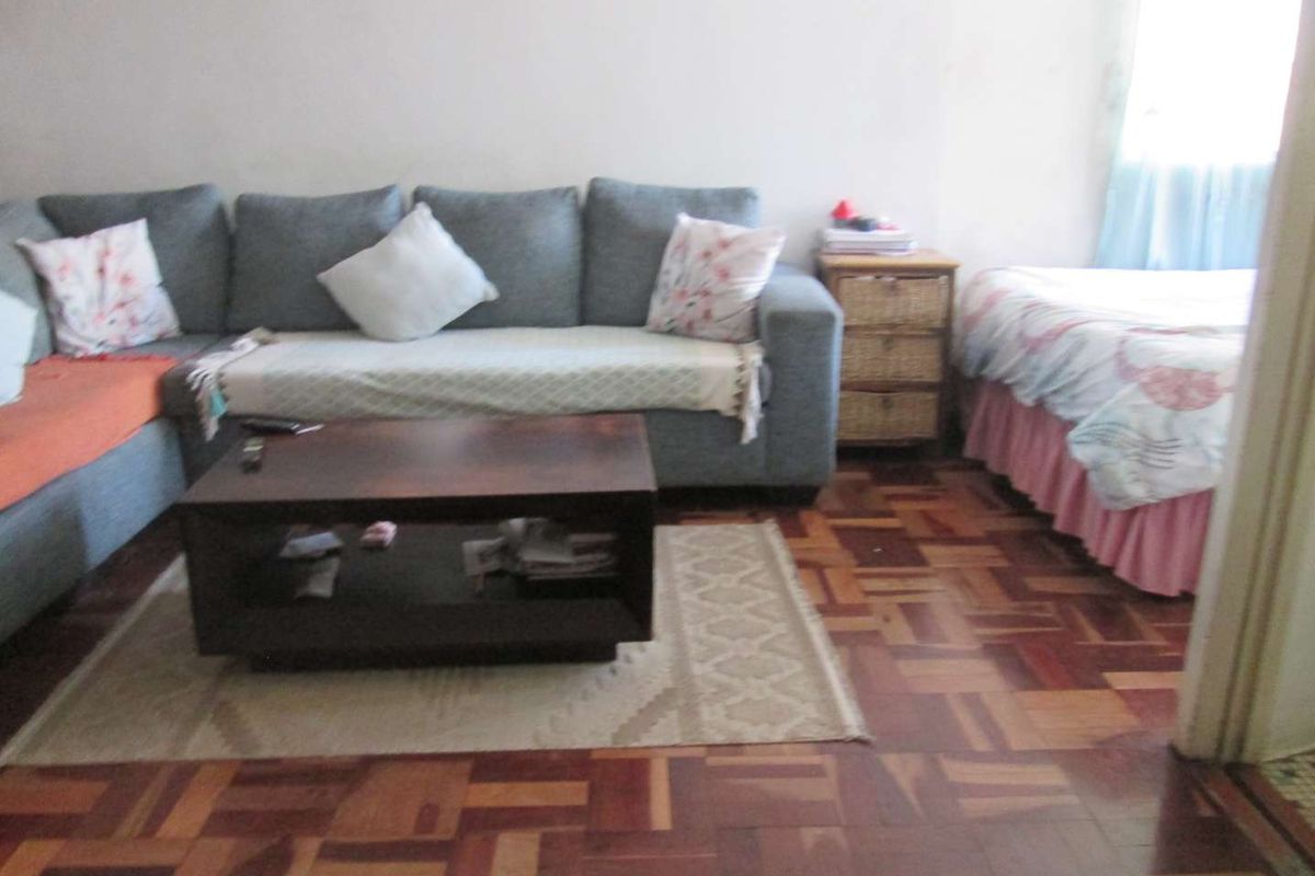 A living area featuring traditional parquet flooring, providing a warm foundation for the space.