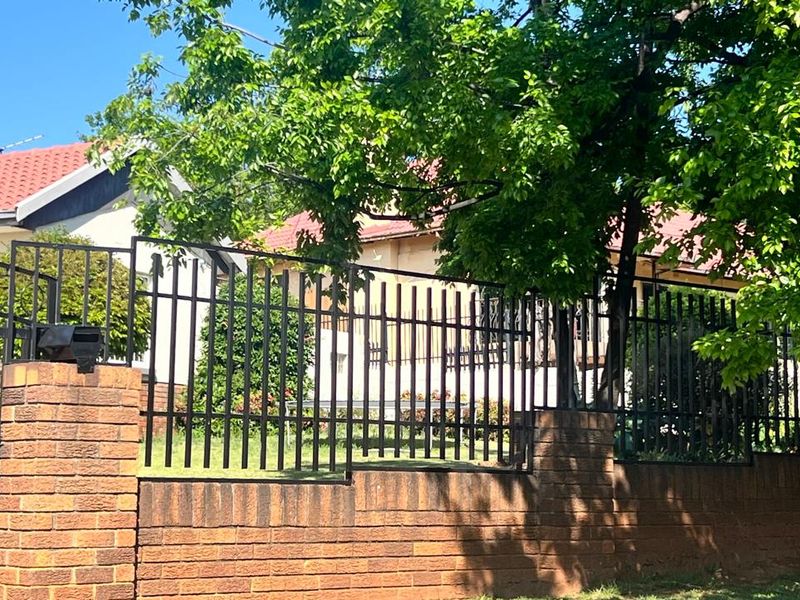 Front view of the cottage property featuring a brick boundary wall with integrated metal security fencing and a tiled roof.
