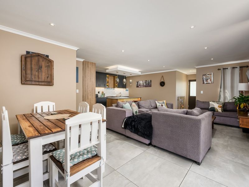 Spacious open-plan living and dining area featuring modern tiled flooring, recessed lighting, and a well-appointed kitchen with a central island.