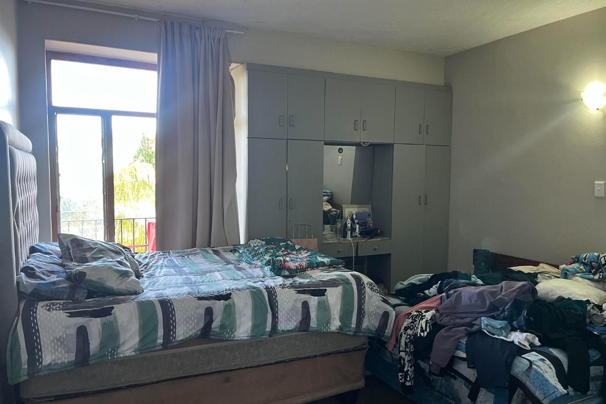 A bedroom featuring built-in floor-to-ceiling cabinetry with a central vanity area and direct access to a balcony through a glass door.