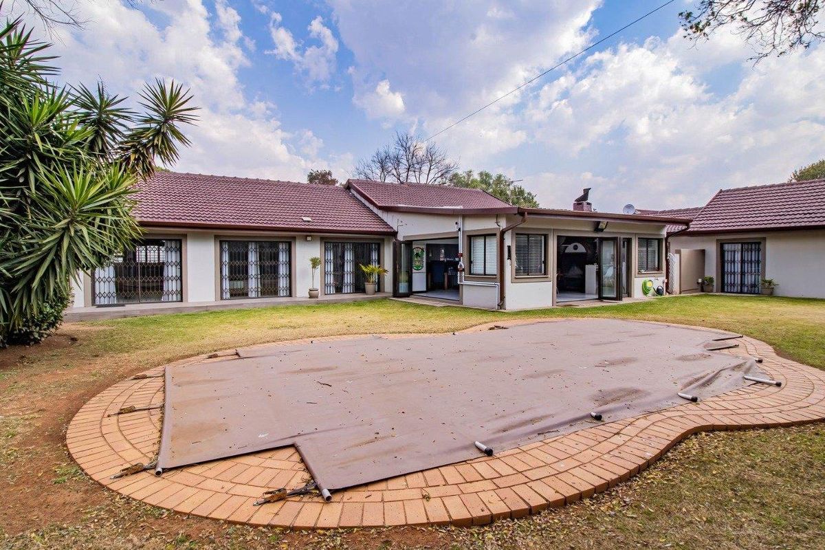 Rear view of the property featuring a swimming pool with a cover, brick coping, and direct access to the home via sliding doors.