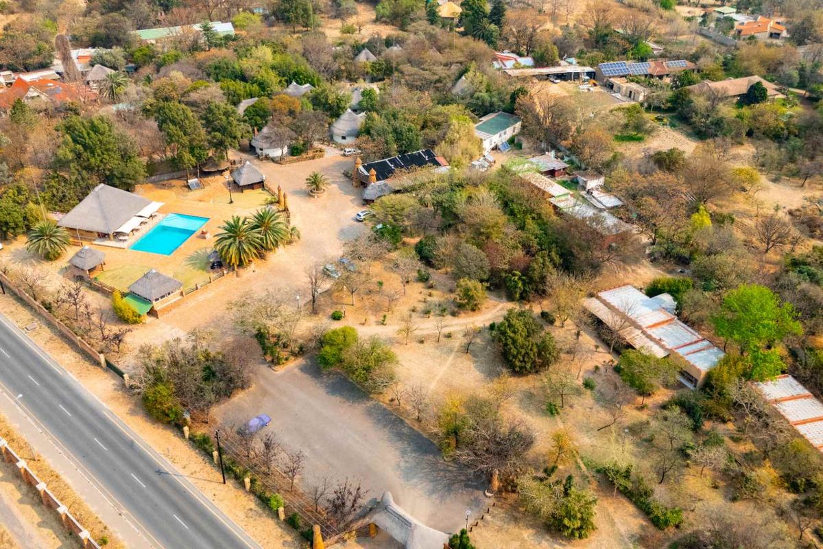 Aerial view of a large farm property featuring multiple structures, a swimming pool, extensive grounds, and direct road access.
