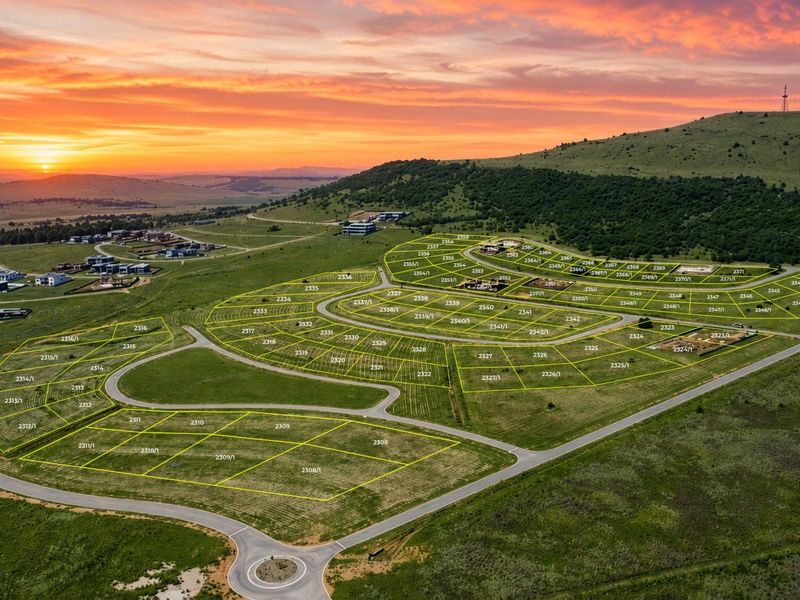 Aerial view of a residential estate development featuring demarcated vacant land plots and established road infrastructure at sunset.