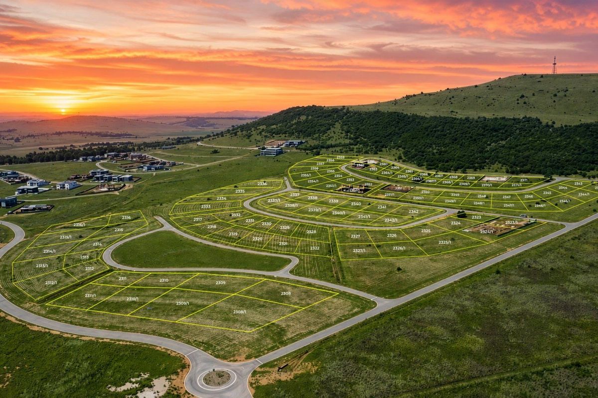 Aerial view of a residential estate development featuring demarcated vacant land plots and established road infrastructure at sunset.
