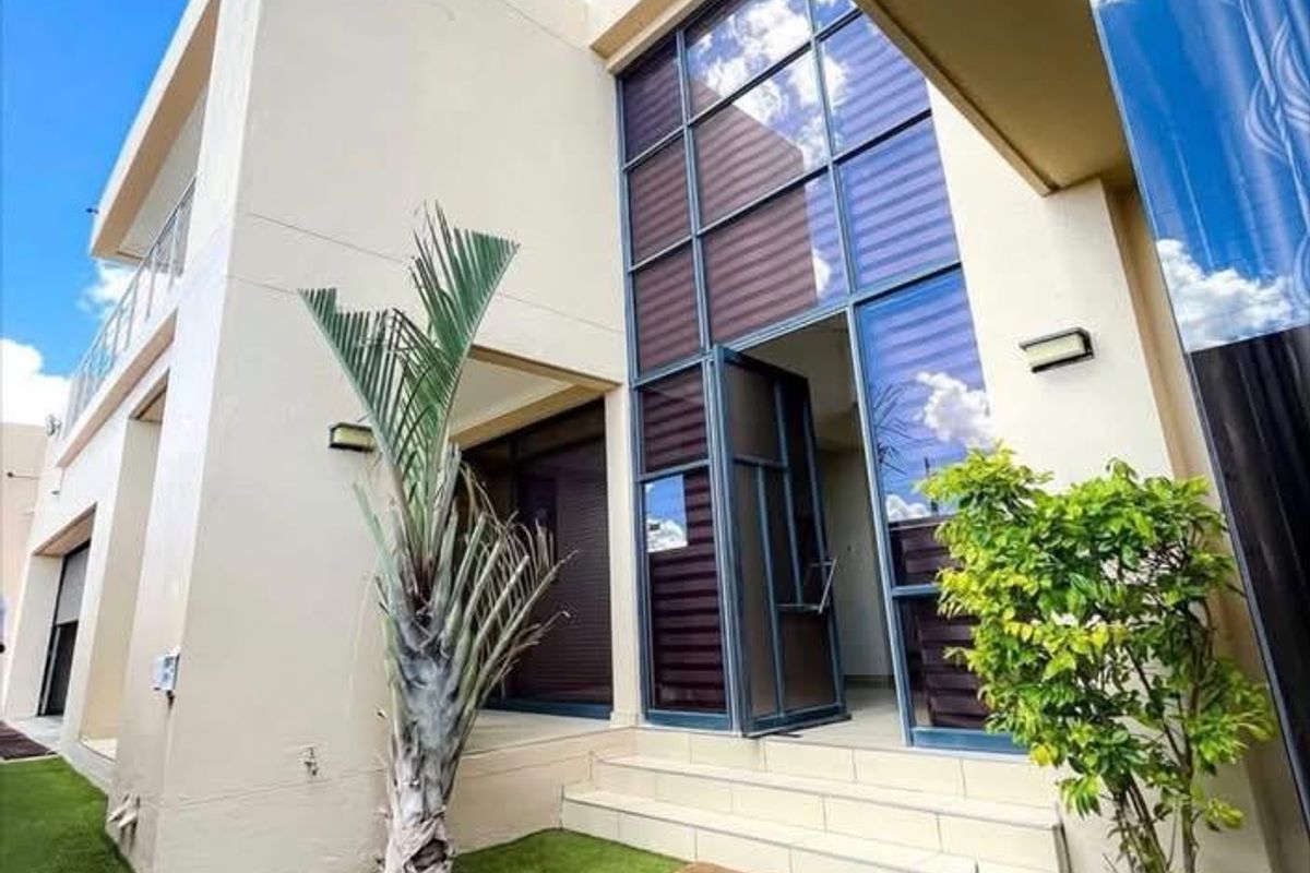 Modern exterior rear view featuring large glass windows, a paved entrance with steps, and a landscaped garden area.