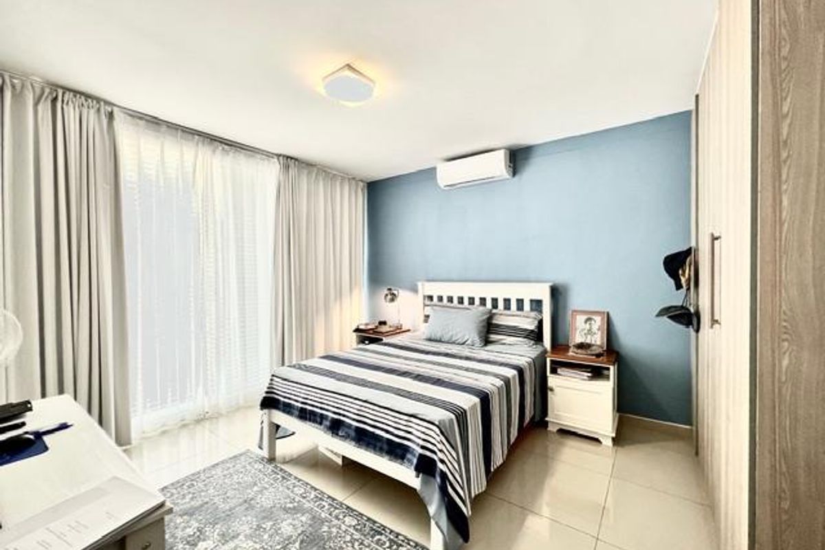 A well-maintained bedroom featuring tiled flooring, a built-in wardrobe, a split-system air conditioner, and large sliding glass doors providing ample natural light.