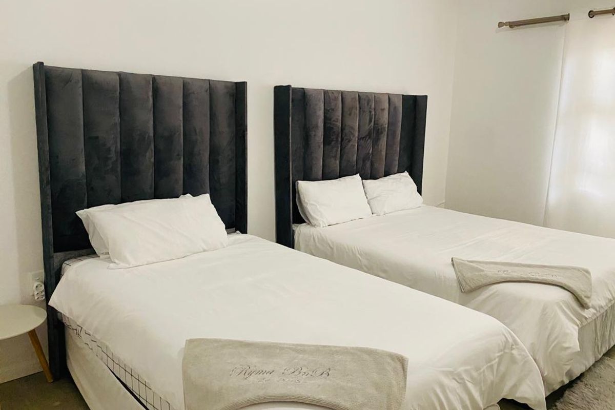 A clean and well-maintained bedroom featuring neutral walls and a curtain rod, providing a comfortable and functional sleeping space.