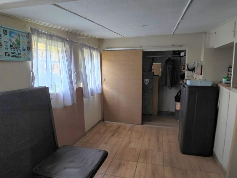 A bedroom featuring tiled flooring, a sliding door, and built-in storage, currently requiring cosmetic updates to improve the overall finish.