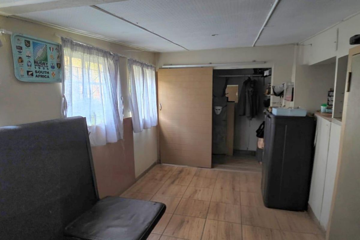 A bedroom featuring tiled flooring, a sliding door, and built-in storage, currently requiring cosmetic updates to improve the overall finish.