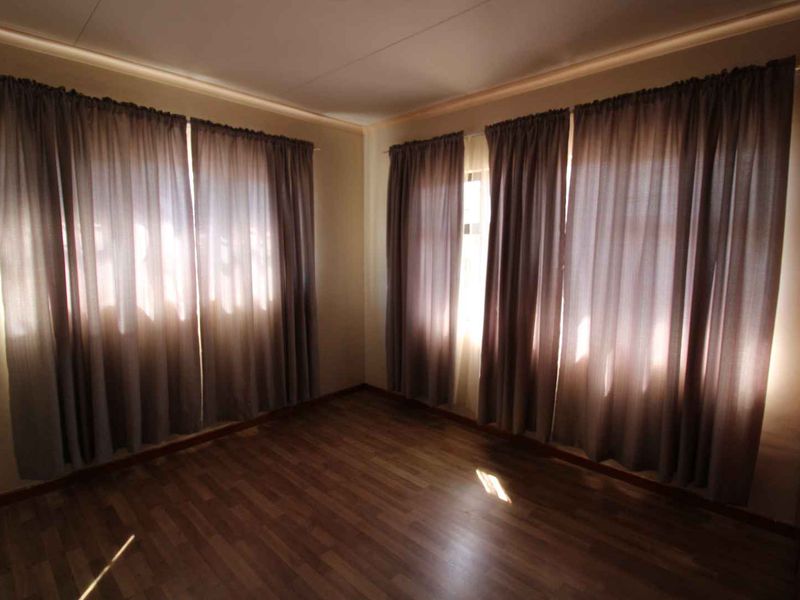 A vacant bedroom featuring laminate flooring and a built-in cupboard, offering a neutral canvas for personalization.