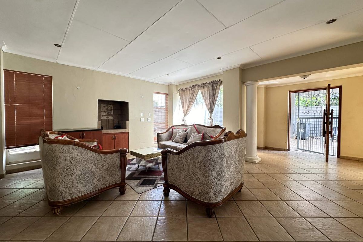 Spacious living area featuring tiled flooring, a built-in fireplace, and direct access to the exterior through a security gate.