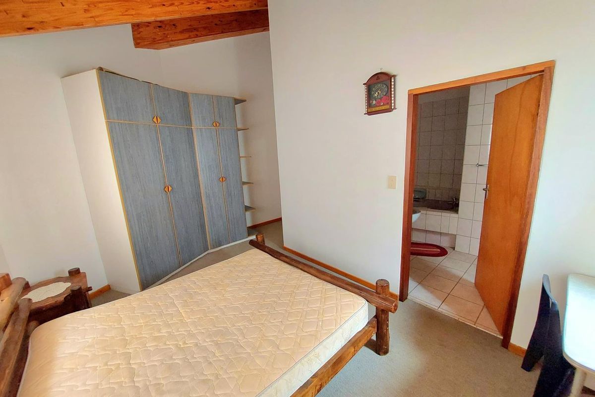 Bedroom featuring exposed timber ceiling beams, built-in wardrobe, and an en-suite bathroom with tiled finishes.