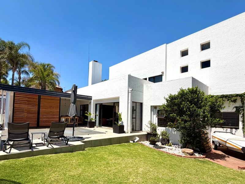 Rear view of the property featuring a covered patio with timber screens, sliding door access, and a well-maintained garden area.
