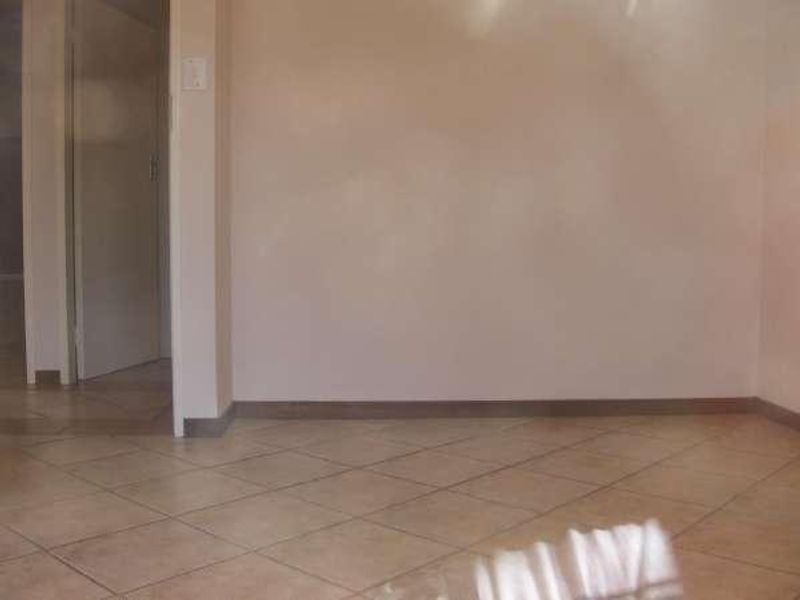 An empty living area featuring neutral tiled flooring and plain walls, providing a blank canvas for interior design updates.