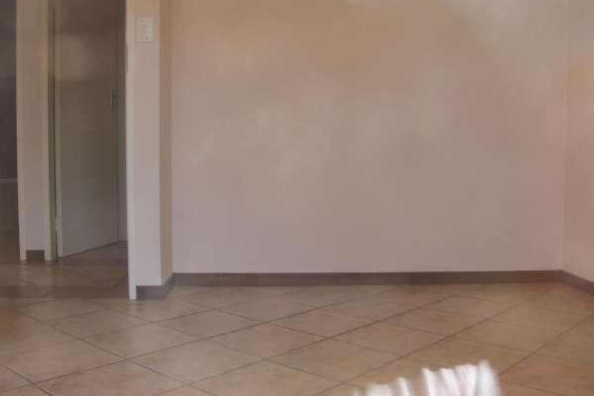 An empty living area featuring neutral tiled flooring and plain walls, providing a blank canvas for interior design updates.