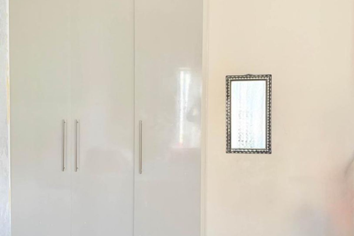 A bedroom featuring built-in floor-to-ceiling cabinetry with a neutral finish and polished tile flooring.