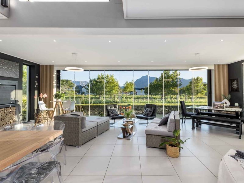 Spacious open-plan living area featuring large floor-to-ceiling glass doors, modern tiled flooring, and a built-in fireplace with scenic mountain views.