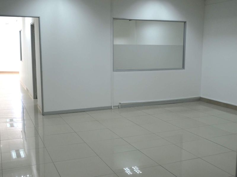 A clean, vacant office space featuring polished tiled flooring, neutral walls, and an internal glass partition, suitable for a professional workspace.