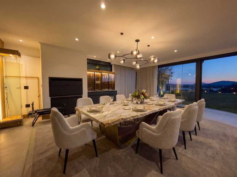 Elegant dining room featuring a stone-topped table, built-in cabinetry, and expansive floor-to-ceiling glass doors offering scenic outdoor views.