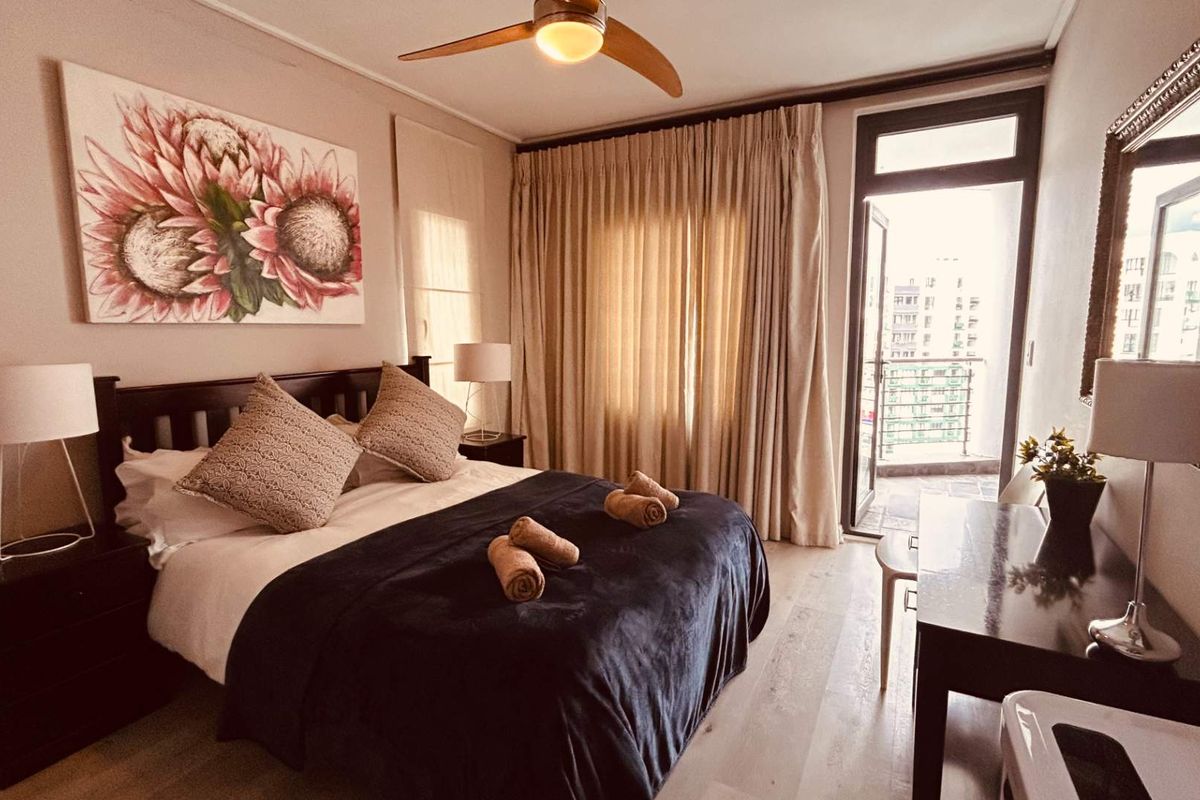 A well-maintained bedroom featuring laminate flooring, a ceiling fan, and direct access to a private balcony.