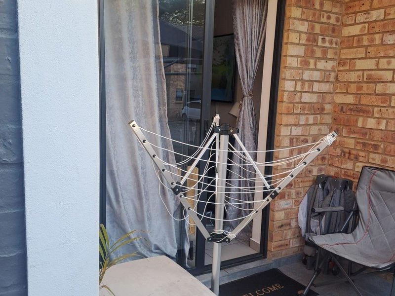 A small outdoor patio area featuring exposed brickwork, tiled flooring, and a sliding glass door providing access to the interior living space.