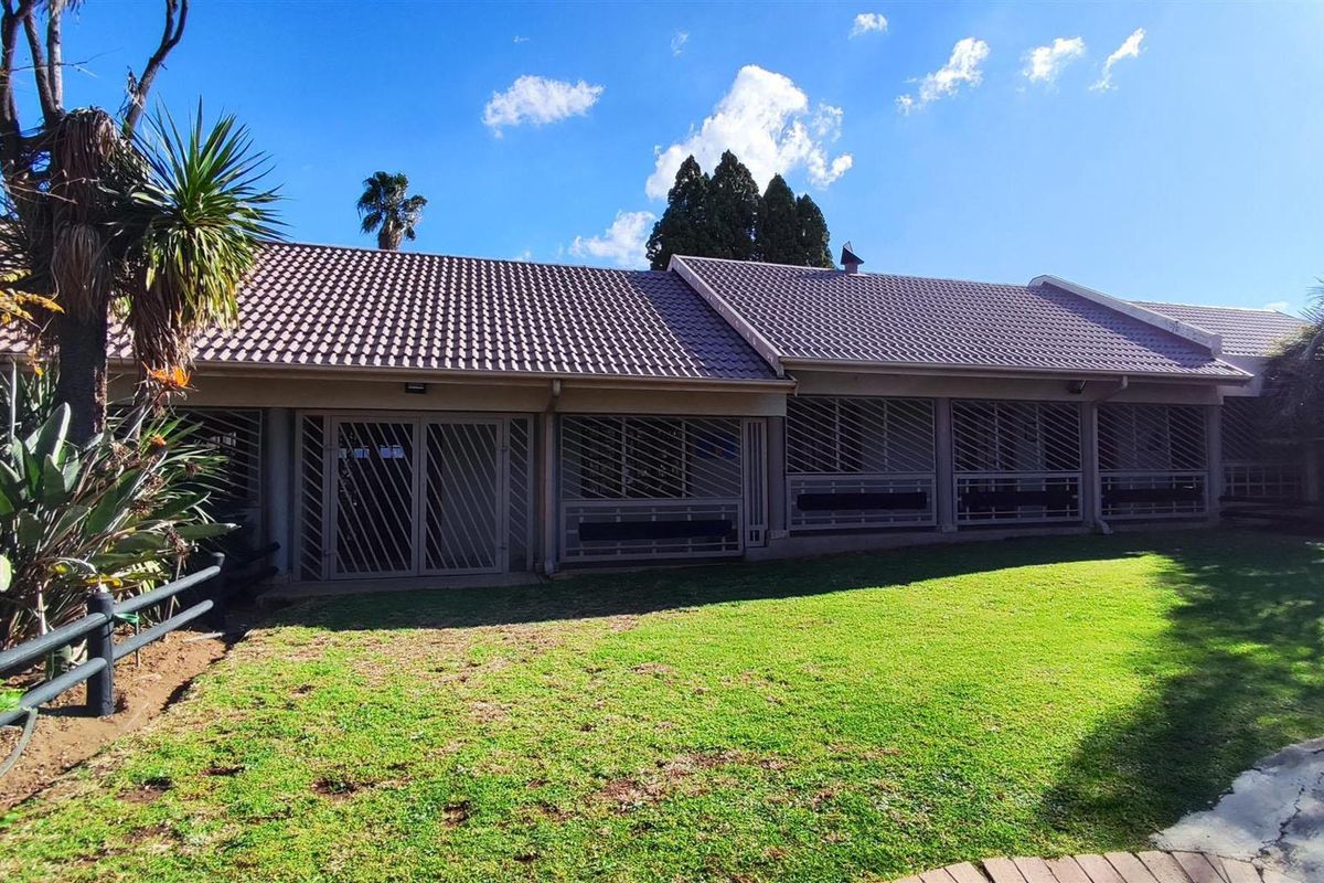 Rear view of the property featuring a tiled roof, security-fitted windows and doors, and a well-maintained garden lawn.