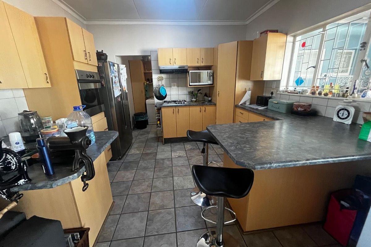 A functional kitchen featuring light wood cabinetry, dark laminate countertops, a built-in oven, and a breakfast bar area with tiled flooring.