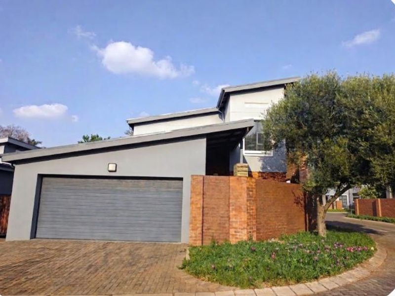 Modern residential exterior featuring a double garage, facebrick accents, and a paved driveway in a well-maintained estate setting.