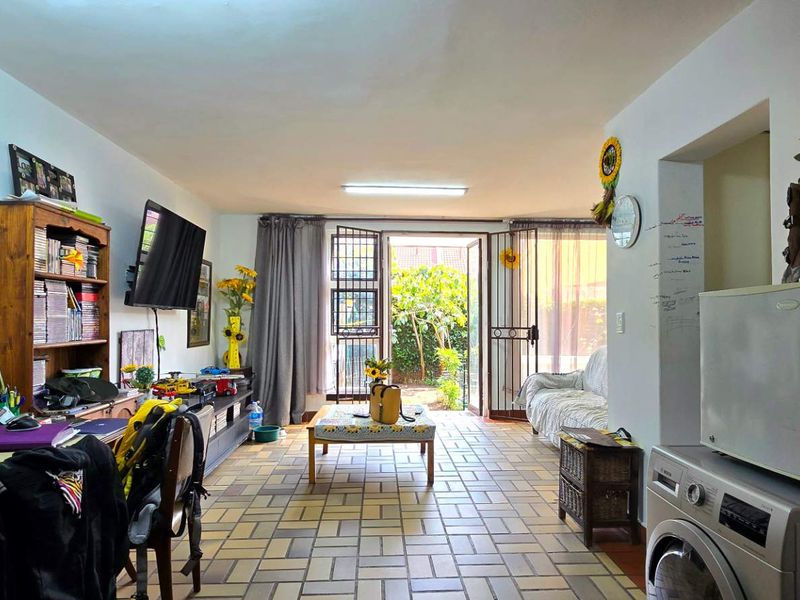 Open plan living area featuring tiled flooring and direct access to the rear garden through a security gate.