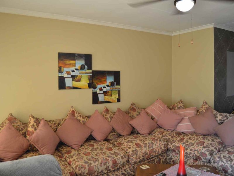 A living room area featuring a ceiling fan and a tiled accent wall, providing a functional space for relaxation.