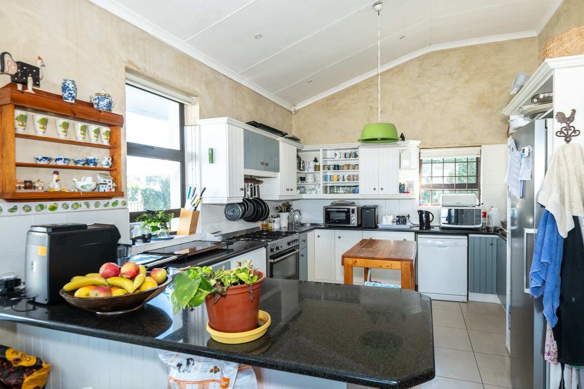 A functional kitchen featuring granite countertops, built-in cabinetry, gas hob, and tiled flooring with a vaulted ceiling.