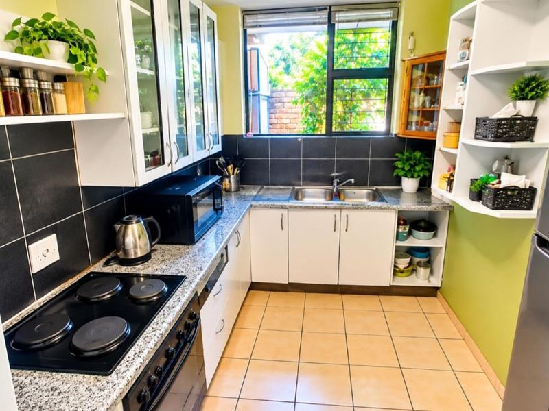A functional kitchen featuring white cabinetry, granite countertops, a double basin sink, and a built-in electric hob and oven with tiled backsplash.