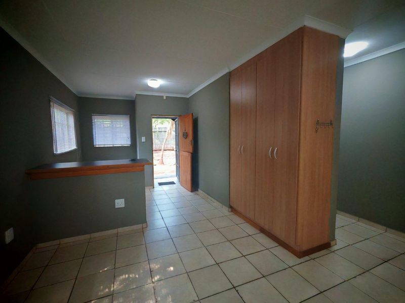 A spacious bedroom featuring tiled flooring, built-in cupboards, and a breakfast bar counter, with direct access to the exterior.