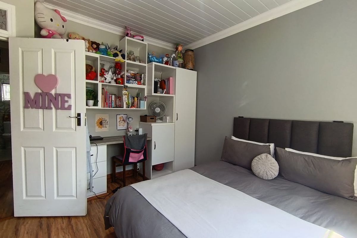 A bedroom featuring laminate flooring, a tongue and groove ceiling, and a built-in desk with integrated shelving storage.