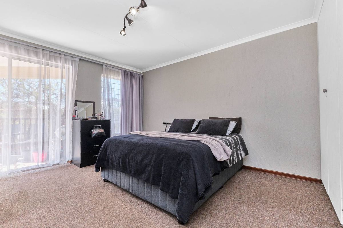 A bedroom featuring carpeted flooring, built-in cupboards, and sliding glass doors providing access to an outdoor area.