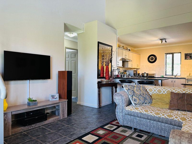 Open plan living area featuring tiled floors and a functional kitchen with breakfast bar, providing a connected space for dining and relaxation.