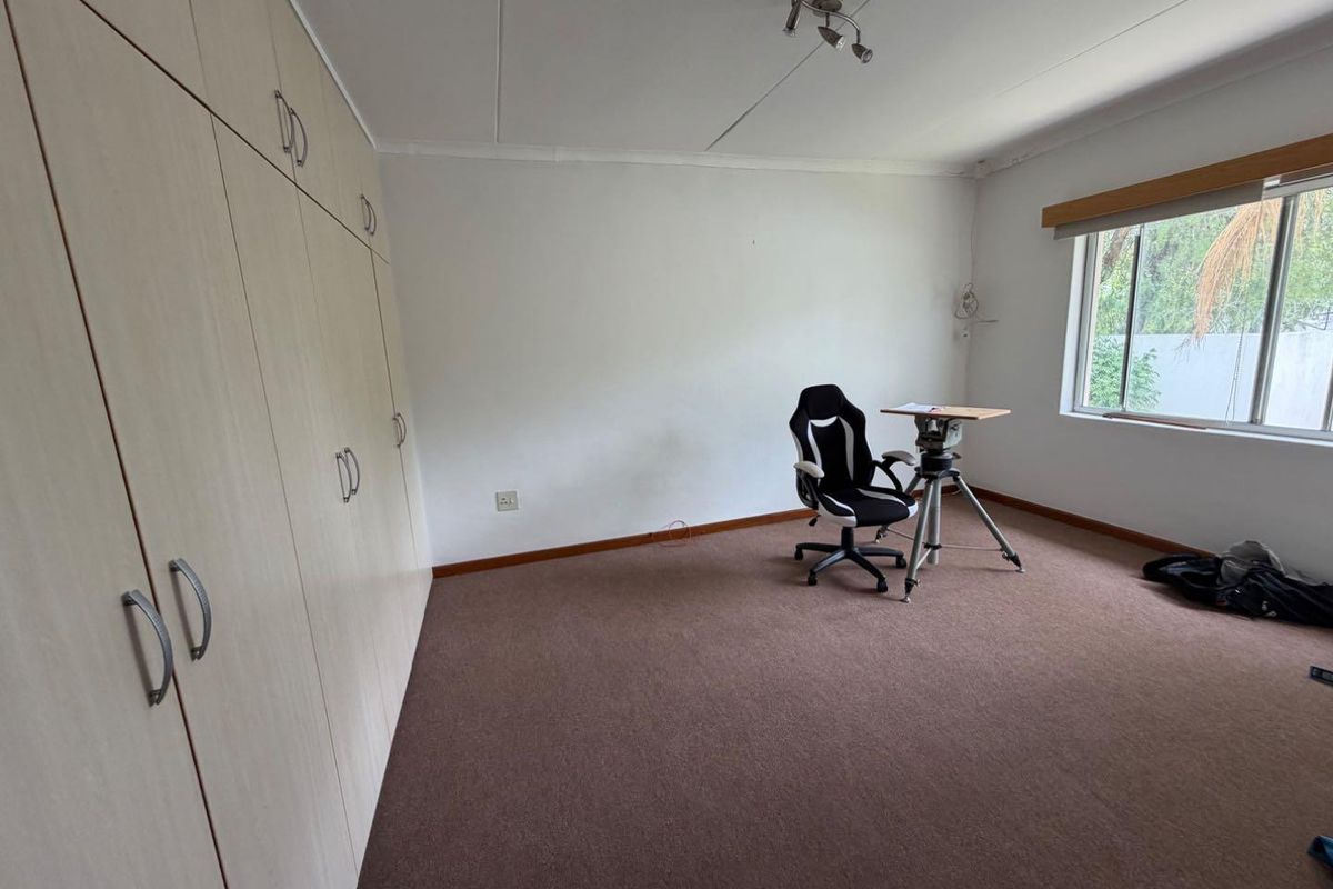 A spacious bedroom featuring extensive built-in cabinetry, neutral carpeting, and large windows providing natural light.