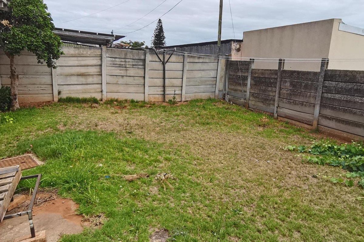 A private rear garden area featuring concrete boundary walls, a water storage tank, and an established lawn space.