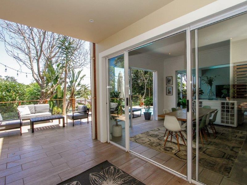 A covered patio featuring tiled flooring and large sliding glass doors that provide seamless access to the indoor dining and living areas.