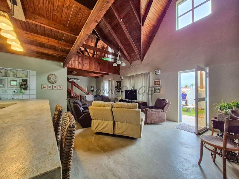 Spacious open-plan living area featuring a high vaulted timber ceiling, mezzanine level, and direct access to the outdoor patio.