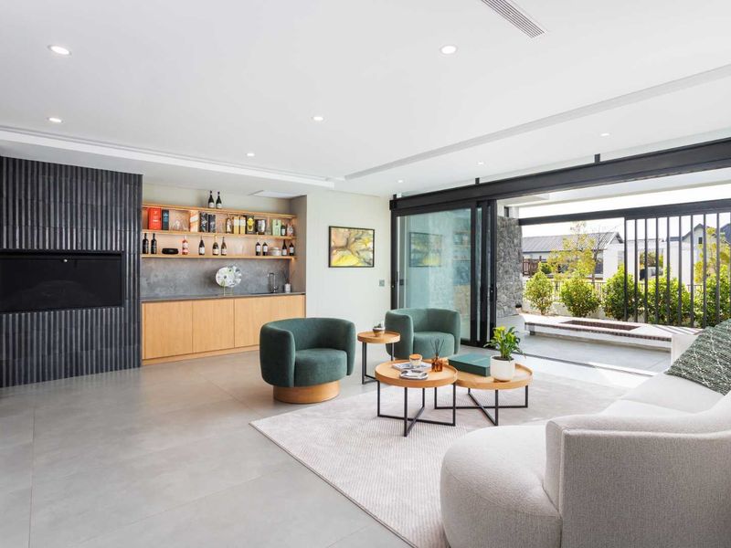 Modern living room featuring a built-in fireplace, custom bar cabinetry, and large sliding doors that open to an outdoor patio area.