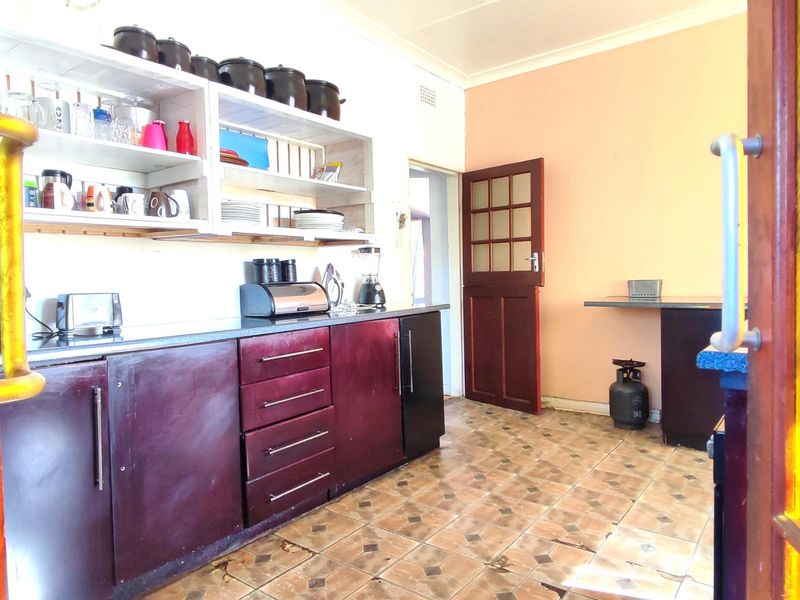 A functional kitchen featuring dark cabinetry, open shelving, and tiled flooring, offering potential for a modern update to enhance the space.