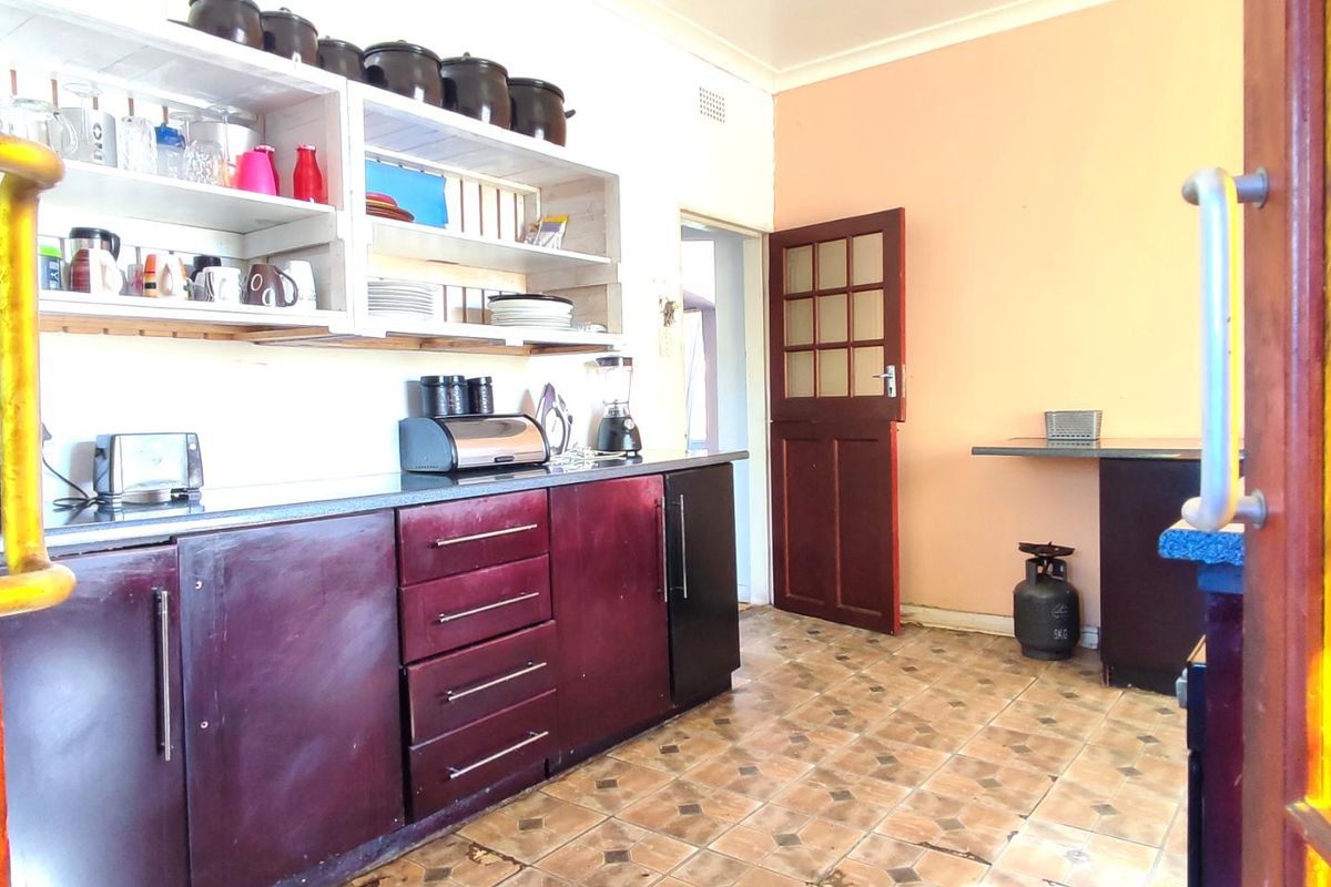 A functional kitchen featuring dark cabinetry, open shelving, and tiled flooring, offering potential for a modern update to enhance the space.
