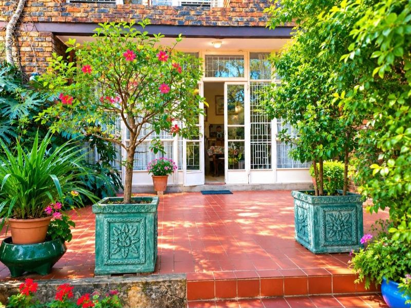 A charming covered patio featuring terracotta tiling and a classic brick facade, providing a seamless transition to the interior living space.