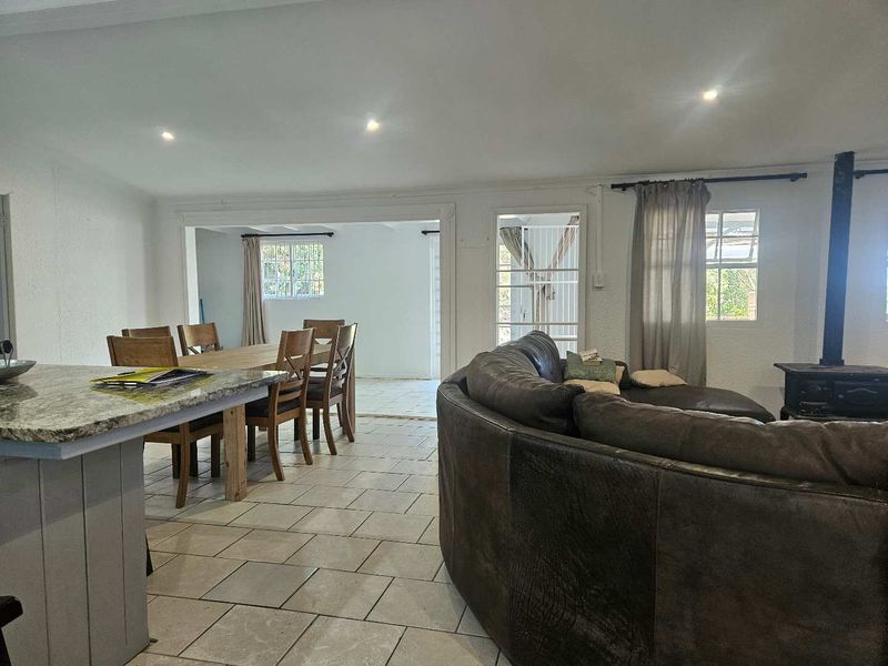 Open plan living and dining area featuring tiled floors, a wood burning stove, and a kitchen island with granite countertops.