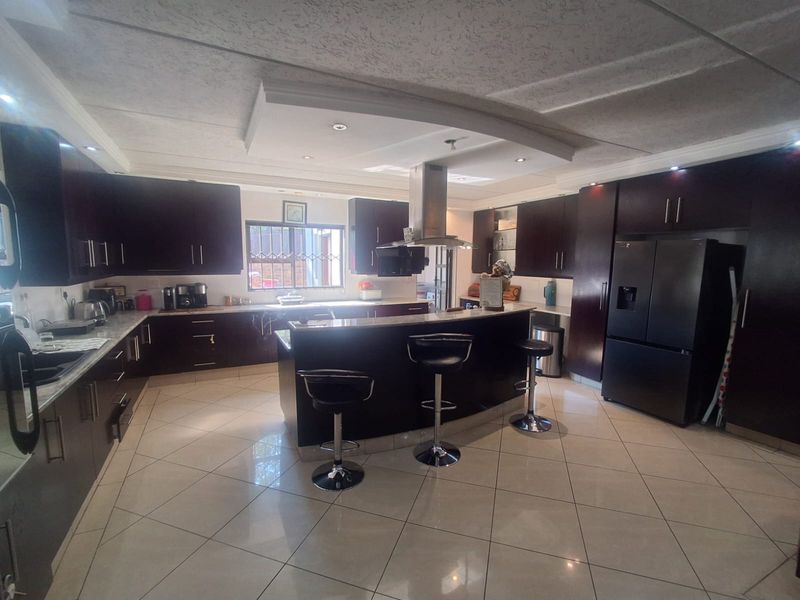 Spacious kitchen featuring dark wood cabinetry, granite countertops, a central island with breakfast bar seating, and modern recessed lighting.