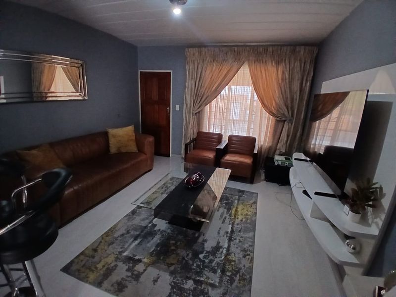 A comfortable living room featuring tiled flooring, a timber door, and neutral wall tones, providing a functional and inviting space for relaxation.
