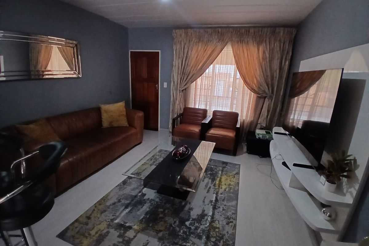 A comfortable living room featuring tiled flooring, a timber door, and neutral wall tones, providing a functional and inviting space for relaxation.