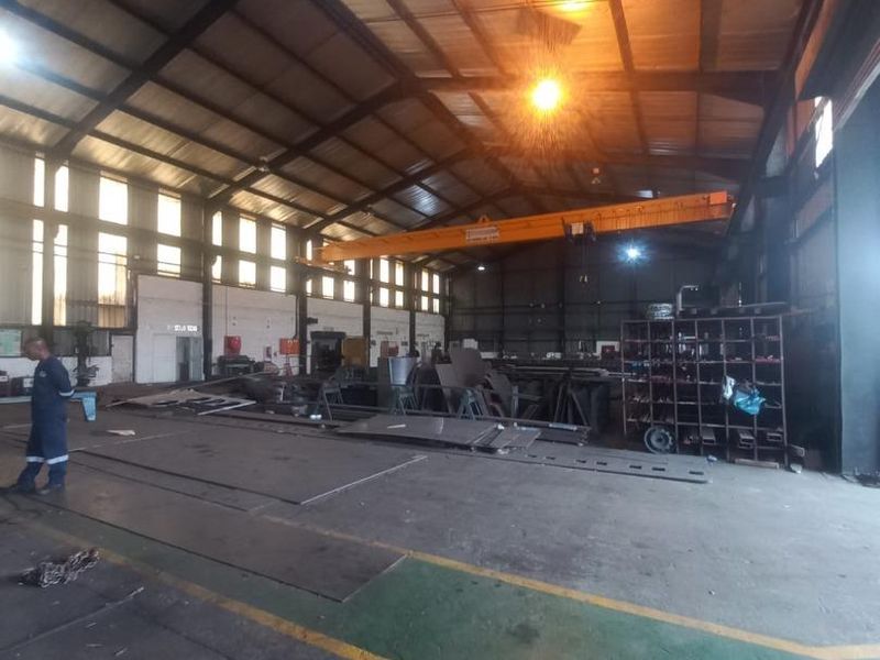 Spacious industrial warehouse featuring a high-clearance steel portal frame, overhead gantry crane, and durable concrete flooring suitable for manufacturing or storage operations.